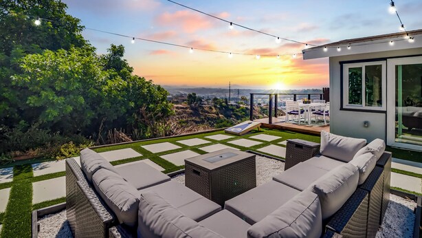 Une terrasse sur le toit avec des sièges extérieurs, une vue sur le coucher du soleil et des guirlandes lumineuses.