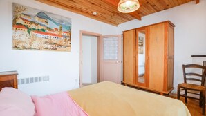 Un dormitorio con una cama, un armario de madera, una silla y un cuadro en la pared.