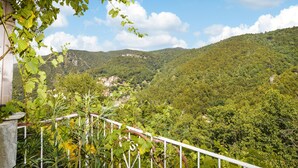 Un balcón con vistas a un valle exuberante y colinas lejanas.