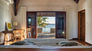 A bedroom with a large bed, a desk with a chair, and a view of the ocean. - Villa Zébra Moon by muse villas  (Bain Boeuf)