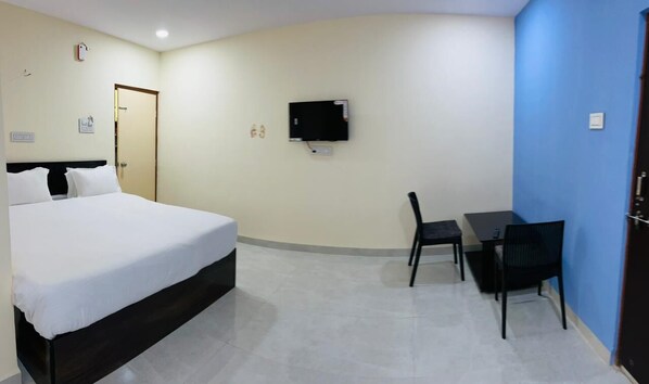 A hotel room with a bed, a desk, a chair, a television, and a door. - Hotel Grand Imperial (Chhatrapati Sambhajinagar)