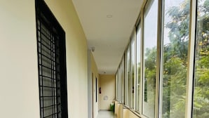 A corridor with large windows on one side, a fire extinguisher, and a trash bin. - Hotel Grand Imperial (Chhatrapati Sambhajinagar)