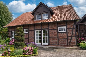 Traditional half-timbered house with a central entrance and beautifully maintained garden.