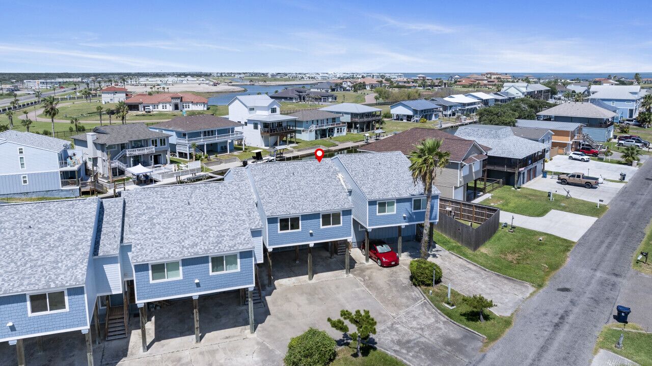 A residential area with multiple two-story houses, a parking lot, and a clear view of the ocean.