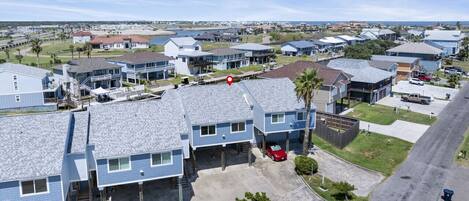 A residential area with multiple two-story houses, a parking lot, and a clear view of the ocean.