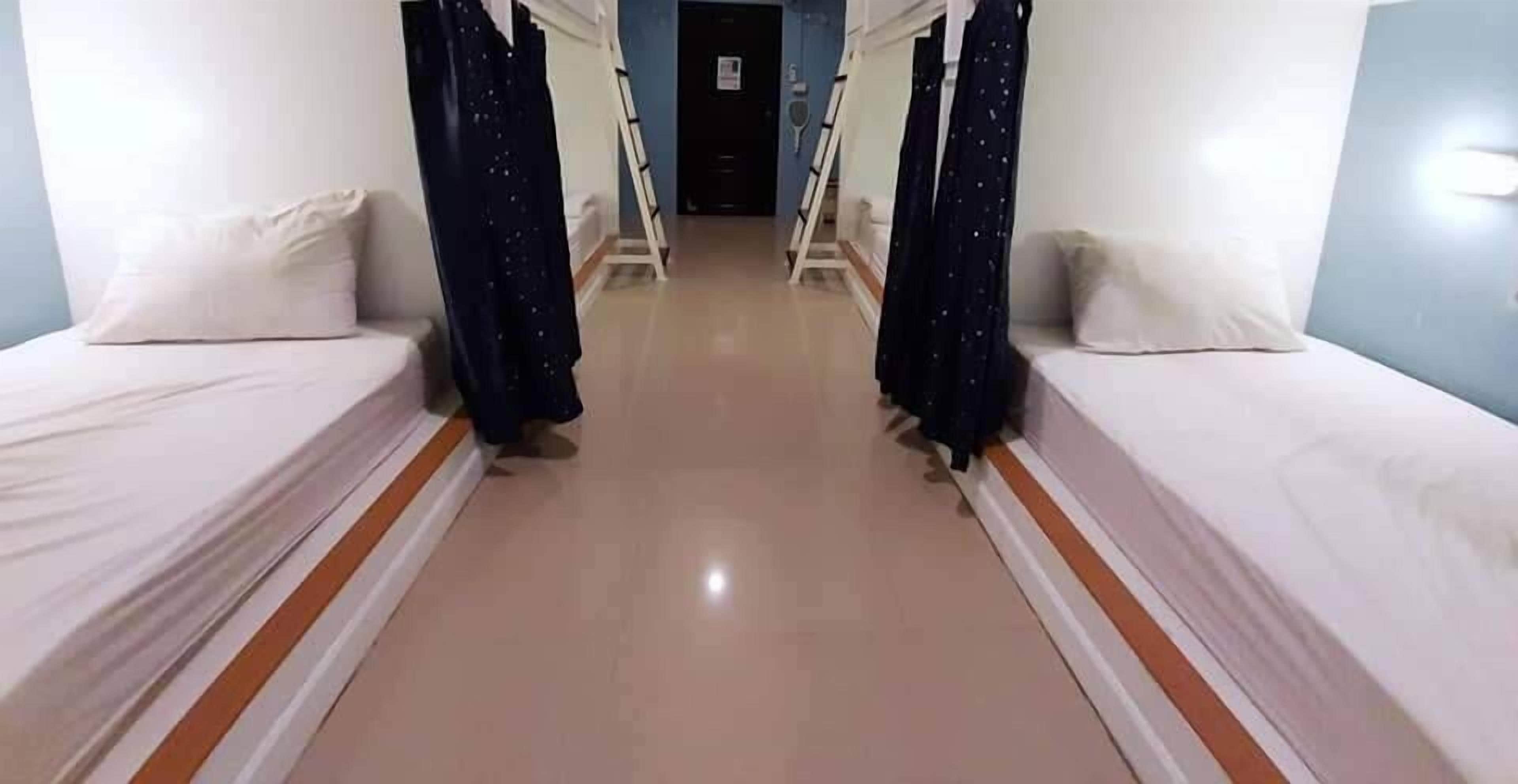 A hotel room with two beds, a tiled floor, and a door in the background.