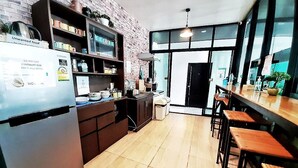 A modern kitchen with a brick wall, stainless steel appliances, and wooden bar stools. - Mercy Hostel (Chiang Rai)