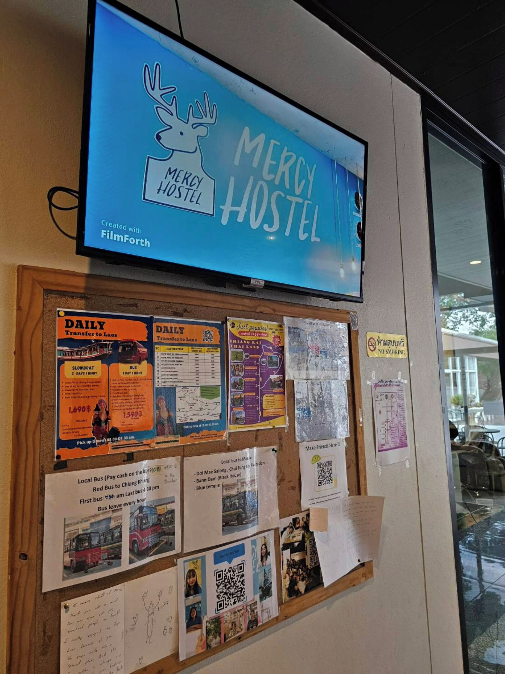 Un panneau d’affichage contenant diverses informations sur les voyages et une enseigne indiquant l’auberge de jeunesse Mercy.
