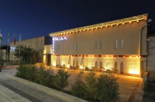 A hotel with a sign that reads 'Hotel' and a well-lit outdoor seating area with tables and chairs.