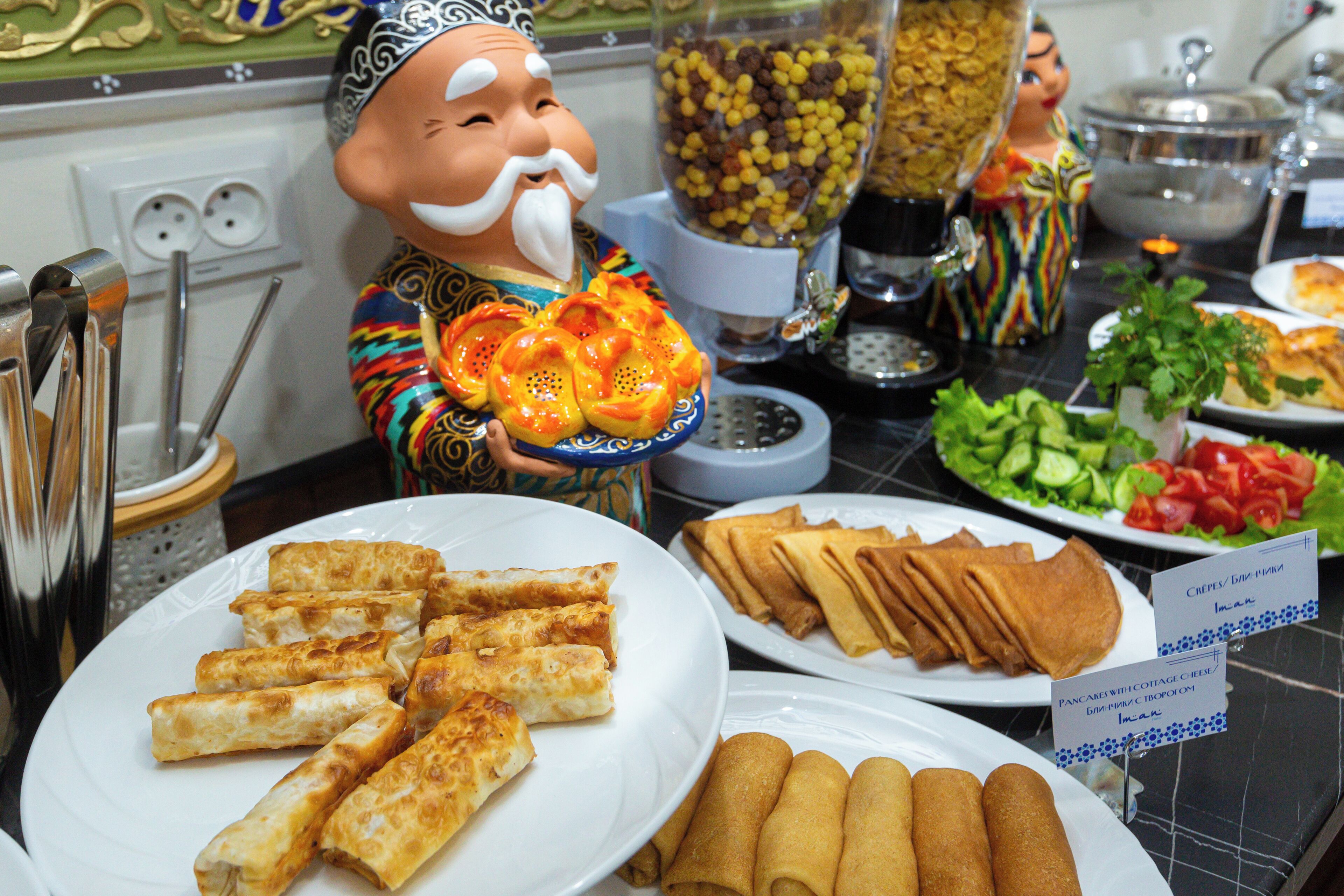 A buffet table with various food items including spring rolls, crepes, and a salad.