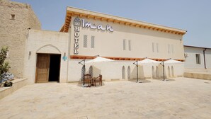 A hotel with a sign reading "Imane Hotel" and a courtyard with outdoor seating and umbrellas. - Hotel Iman (Bukhara)