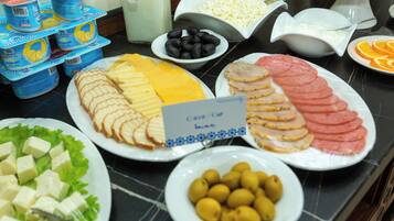 A buffet with various food items including cheese, ham, olives, and yogurt.