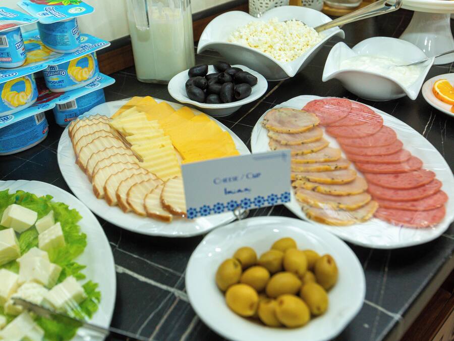 A buffet with various food items including cheese, ham, olives, and yogurt.