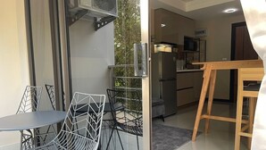 A modern kitchen with a built-in microwave and a wooden dining table. - Cosy 1-bedroom apartment in a pleasant walking location to Yanui beach  (Tambon Rawai)