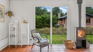 Un salon chaleureux avec une cheminée, un panier en osier et un fauteuil placé près des portes-fenêtres coulissantes.