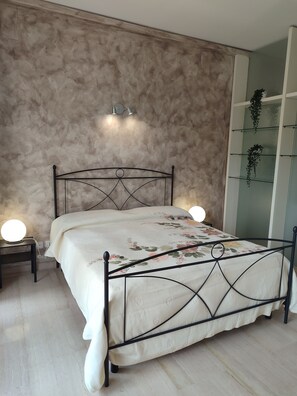 Cozy retreat with a bed, bedside tables, and a shelving unit, perfect for unwinding.