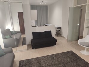 Relax in a clean, minimalist space with a black sofa, grey sofa, and a spacious desk area.