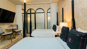 A hotel room with a bed, two chairs, a small table, a TV, and a wall with a brick pattern. - Room deluxe double bed with communal pool Ma3 (Ciudad de Panamá)