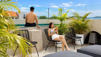 Une terrasse sur le toit avec une piscine, des chaises longues et des plantes en pot.