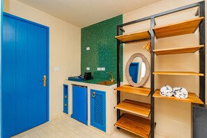 A room with a blue door, a green tiled backsplash, a sink, a mirror, and wooden shelves. - Room Superior with communal pool Ma11 (Ciudad de Panamá)