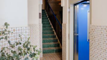 A staircase with green tiles leading to a blue door, surrounded by patterned walls.