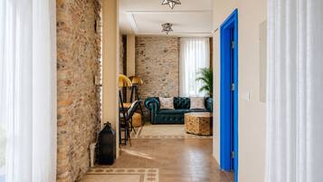 A hallway with a stone wall, a blue door, a green sofa, and a patterned rug.
