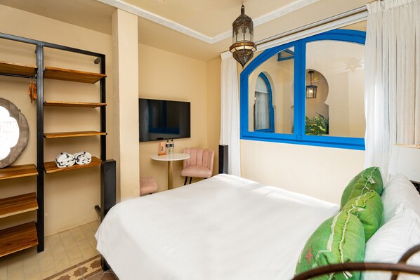 Ein Hotelzimmer mit Bett, Fernseher, kleinem Tisch und Stuhl.