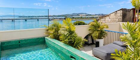 Una piscina en la azotea con vistas al agua y colinas distantes.