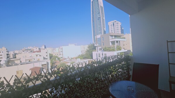 A balcony with a view of a cityscape, including modern buildings and a clear sky.