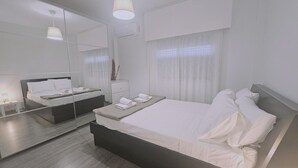 A modern hotel room with a large bed, a bedside table, a mirror, and a window with curtains. - STAY Limdream Apartment (Limassol)