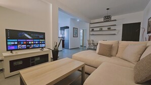 A modern living room with a flat-screen TV, a beige sofa, and a wooden coffee table. - STAY Limdream Apartment (Limassol)