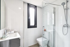 Une salle de bain moderne avec une douche à parois de verre, des toilettes et un lavabo avec un miroir.