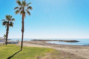 A beach with palm trees, a boat, and a rocky shoreline. - Solaga - Jabega (Málaga)