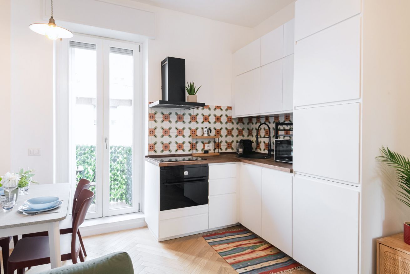 Una cocina moderna con armarios blancos, horno negro y un salpicadero con diseño.