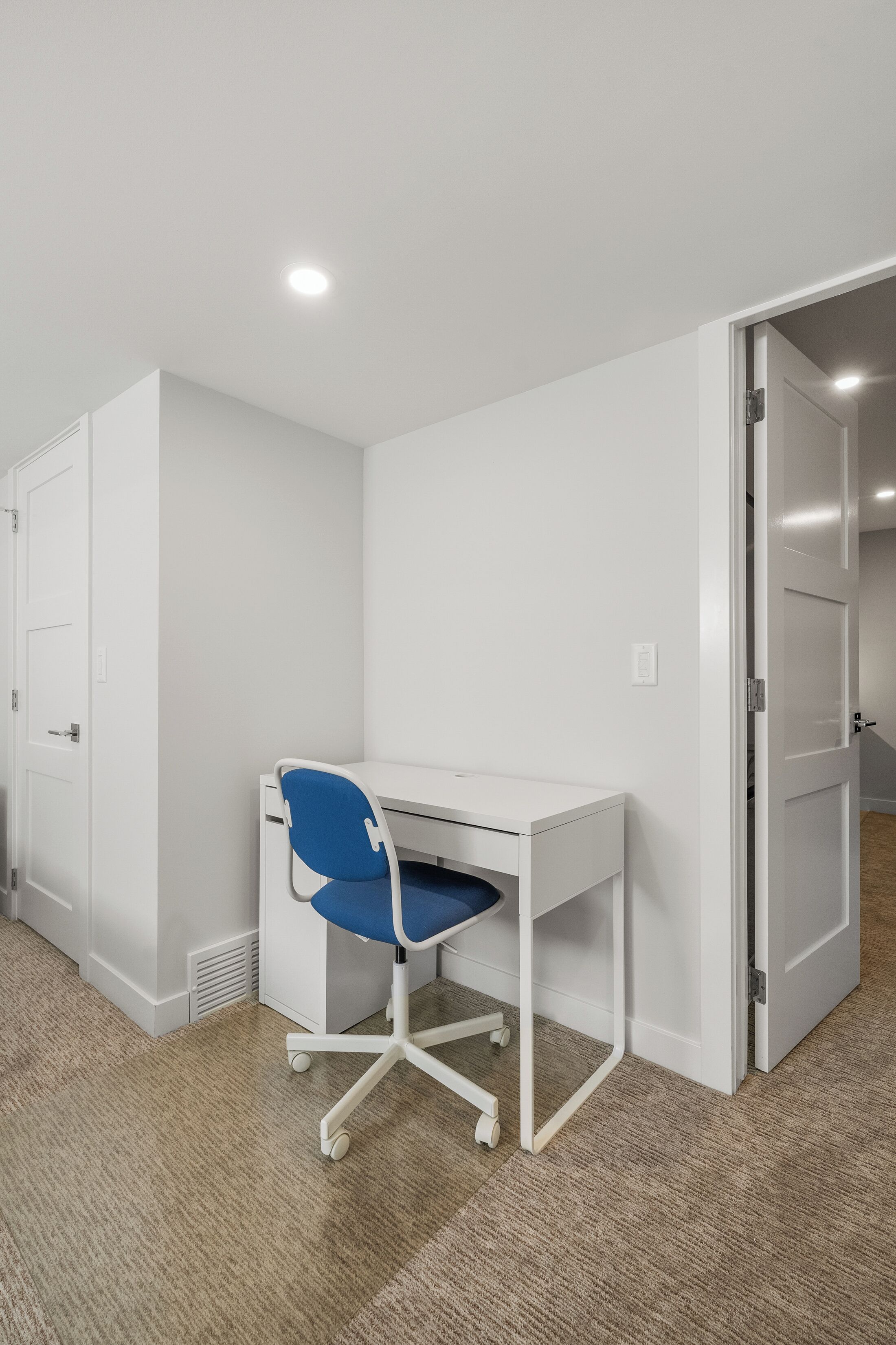 A small, white office space with a desk and a blue chair.