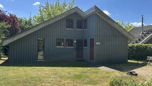 A single-story metal building with a gabled roof, a front door, and a small porch area. - Wildgans 83 - Classic Scandinavian vacation home for up to 6 people (Mirow)