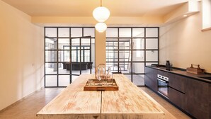 Une cuisine moderne avec un îlot central en bois, de grandes fenêtres et une vue sur la ville.