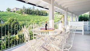 Une terrasse avec une table et des chaises en métal blanc, donnant sur un vignoble.
