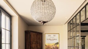 Une pièce spacieuse avec une grande table en bois, un lustre décoratif et une affiche de film accrochée au mur.