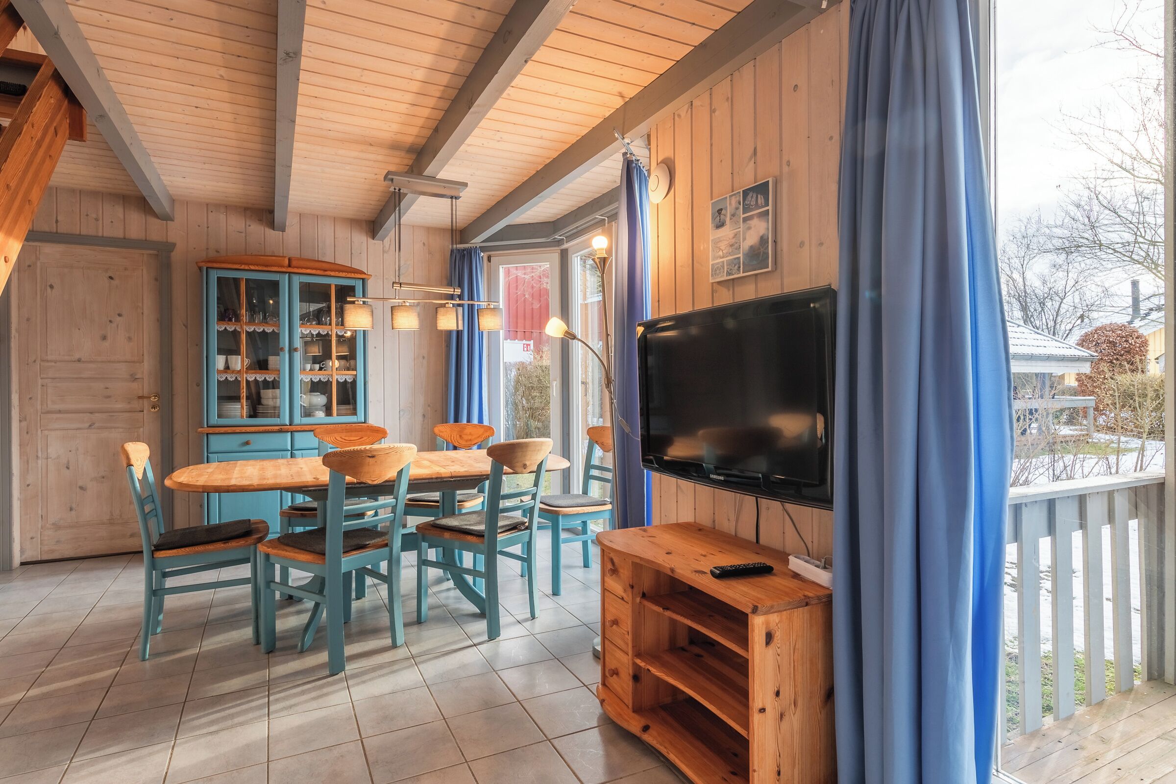 A wooden interior with a dining area, a television, and a view of the outside.
