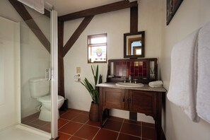 Et badeværelse med toilet, håndvask med spejl og en bruseniche.