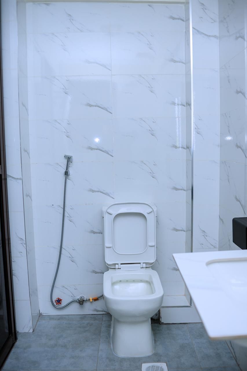 A bathroom with a toilet, a shower, and a sink.