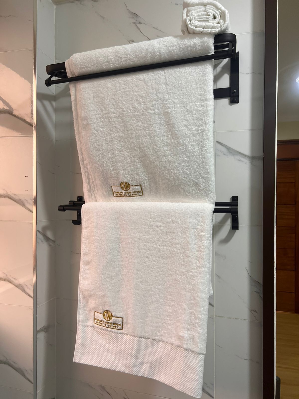 Un perchero con dos toallas blancas, cada una con un logotipo y texto que indican un hotel de lujo.