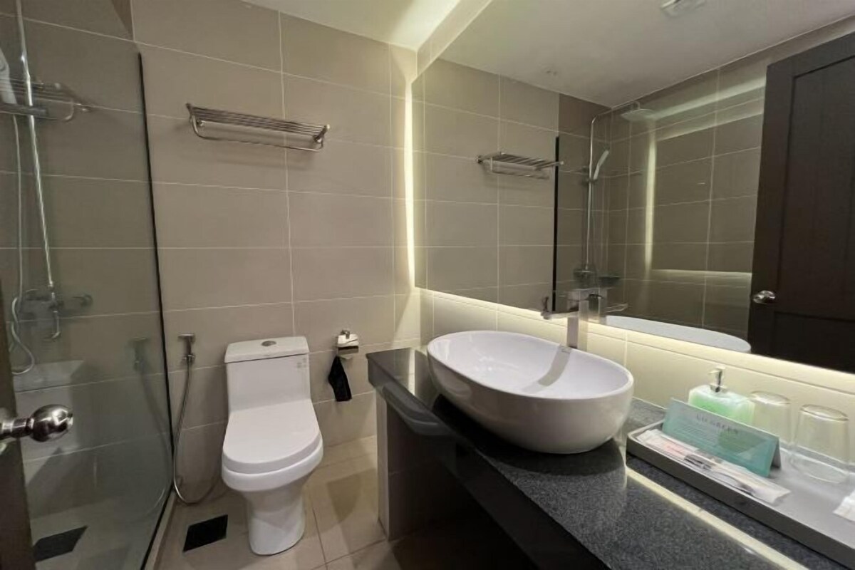A modern bathroom with a toilet, a large sink, and a glass shower enclosure.