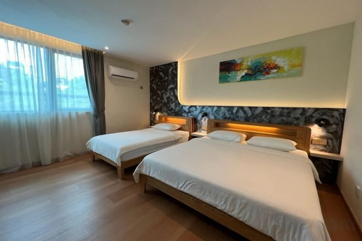 A hotel room with two beds, a painting on the wall, and a window with curtains.
