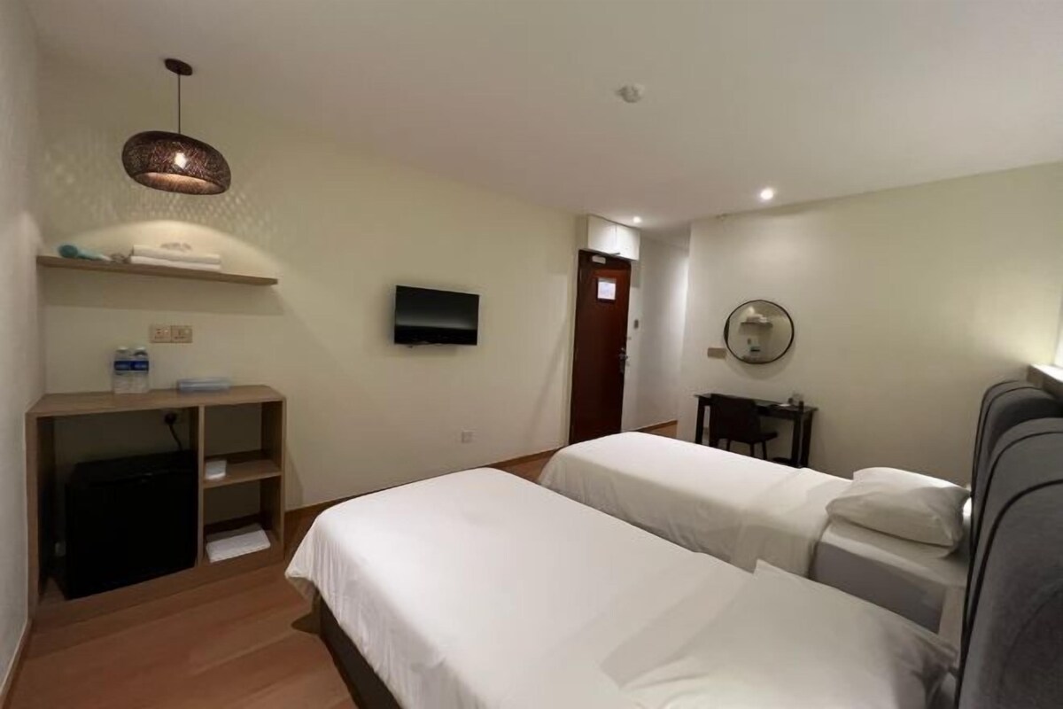 A hotel room with two beds, a TV, a desk with a chair, and a mirror.