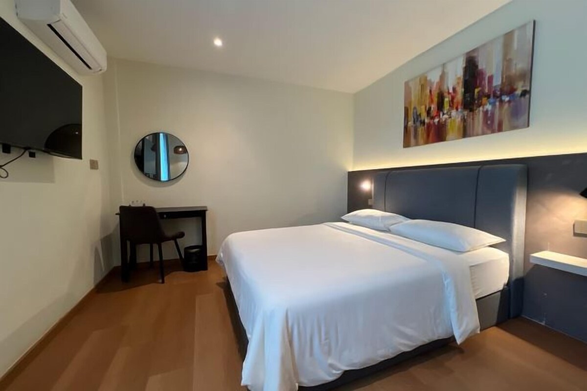A modern hotel room with a large bed, a desk, and a chair.