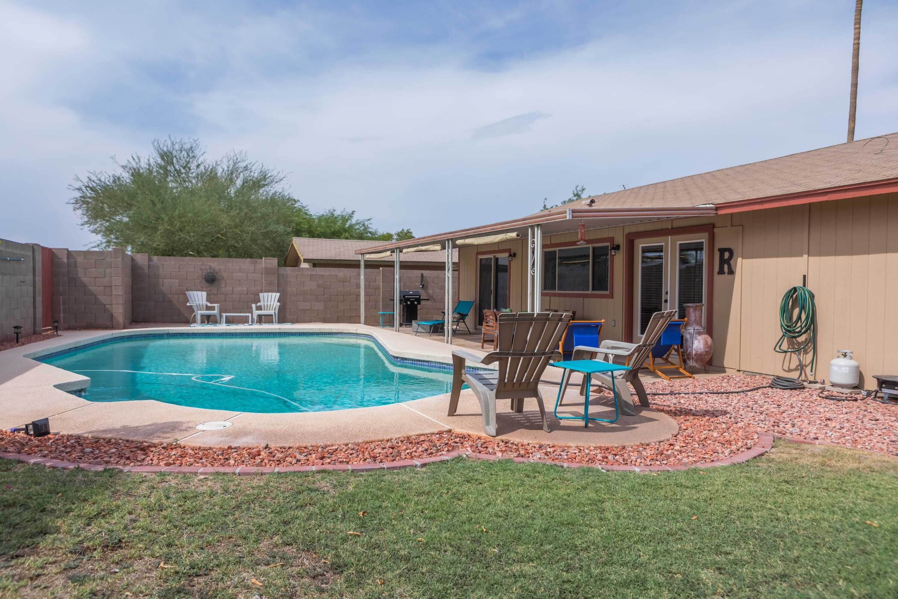 Un jardin avec une piscine, des meubles de patio et un espace couvert.