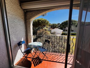 A balcony with a table and chairs, a view of the surrounding area, and a clear sky.
