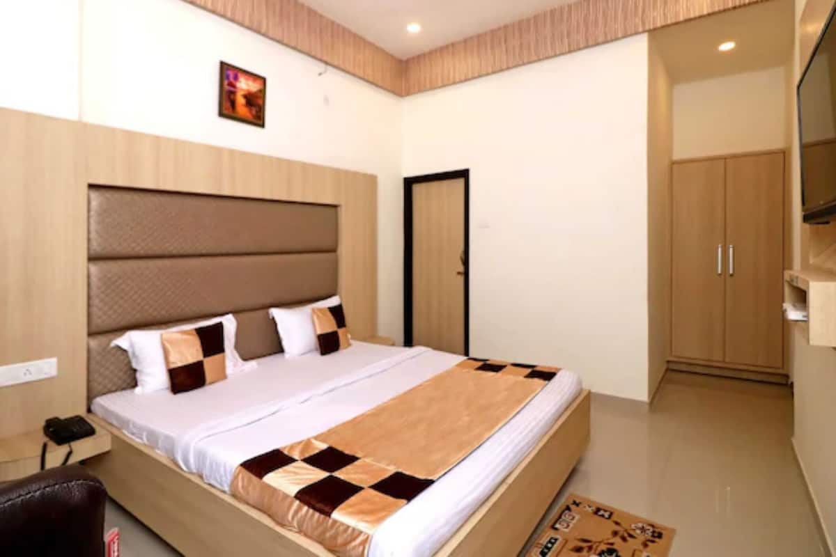 Un dormitorio con cama, armario, televisor y puerta.